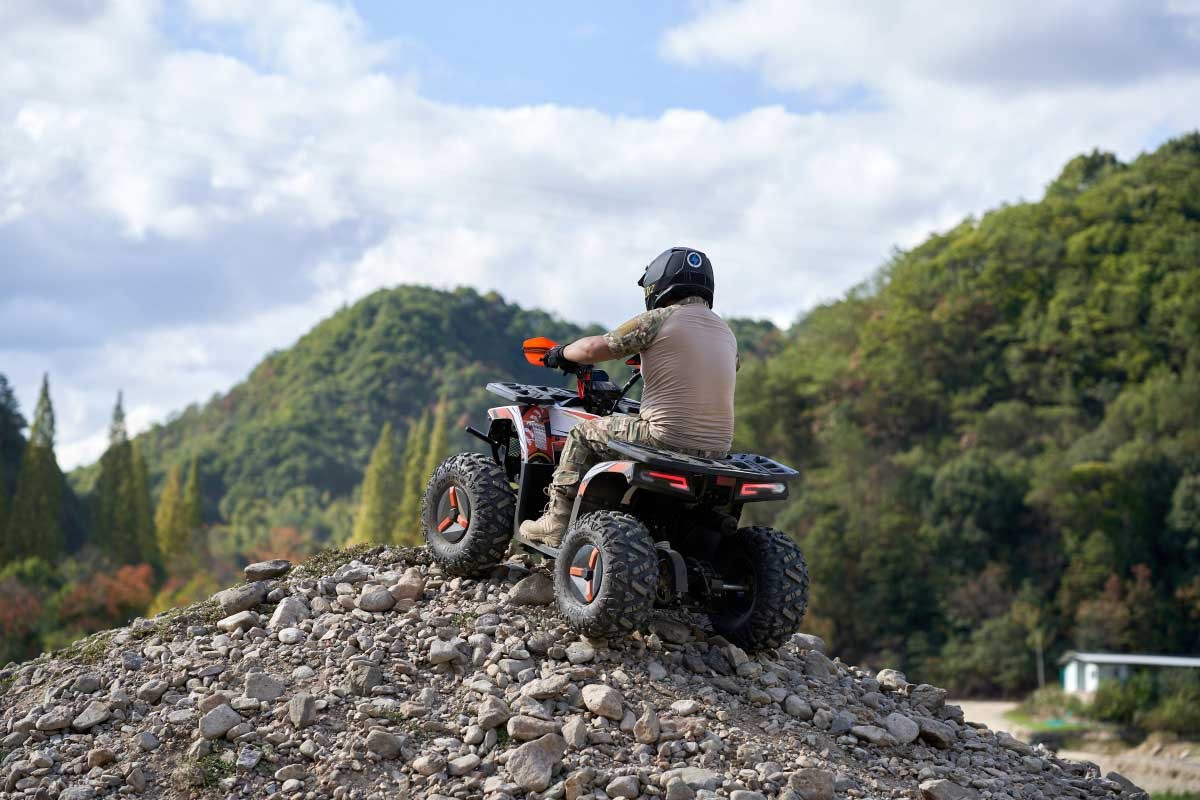 Rider cresting a rocky hill on the 120cc gasoline utility ATV FR125ATV-UT &mdash; trail riding and hill-climb capability